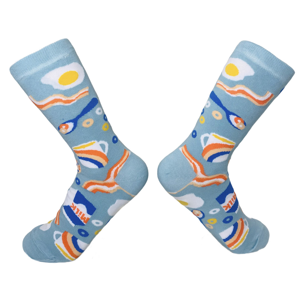 A pair of light blue House Of Shon Eclectic socks featuring a breakfast them of bacon, eggs, coffee, cereal, and milk.